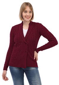 Burgundské pletené sako s dvojitými knoflíky, vzorem z kabelkového úpletu, šálovým límcem a manžetami s žebrováním, v kombinaci s modrými džíny.