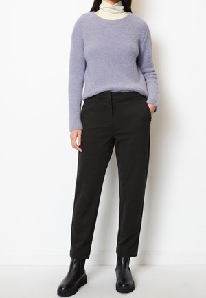Un pull léger violet texturé associé à un pantalon noir élégant et des bottines noires. La silhouette est décontractée avec un design à jambes droites.