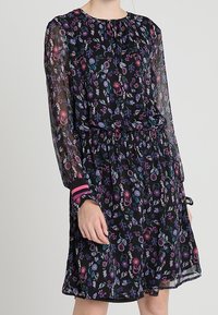 Svart blommig klänning med långa genomskinliga ärmar, samlad midja och färgglad blommönster. Har randiga detaljer på ärmsluten.