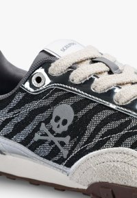 Czarno-szare sneakersy z teksturowanymi kremowymi sznurówkami, metalicznymi detalami i szarym logo czaszki z kośćmi na bocznej części.