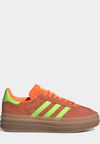 Orange and brown suede sneakers with neon green accents and three stripes. Thick rubber sole, textured tongue, and subtle branding on the side.