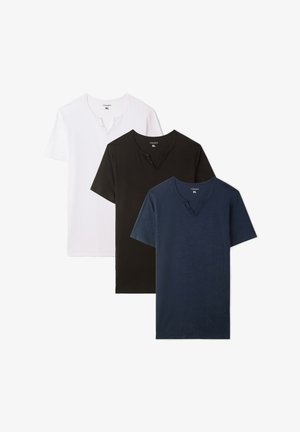 T-shirt a maniche corte blu navy con scollo a V abbinato a pantaloni cargo azzurri chiari con più tasche e sneakers bianche con suola marrone chiaro.