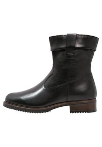 Botte cheville en cuir noir avec un revers roulé, bout arrondi et semelle texturée. Présente une finition lisse et des détails de couture subtils.