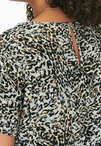 Top a maniche corte con stampa animalier nera, marrone e azzurra chiara. Dettaglio a chiave sul retro con chiusura a bottone. Tessuto morbido e testurizzato.