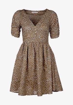 Brąsowa sukienka z krótkim rękawem i dekoltem w kształcie litery V, w białe kropki, z guziczkami oraz rozkloszowanym dołem, zapewniająca luźny krój. Materiał bawełniany.
