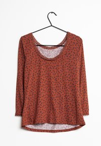 Rödbrun långärmad skjorta med blommönster och spetskant längs med halsringningen och ärmsluten. Rundad fåll och mjuk textur.