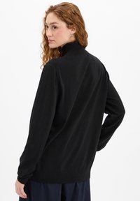 Schwarzer Pullover mit hohem Kragen aus weichem Strickstoff. Er verfügt über lange Ärmel und einen gerippten Saum für zusätzliche Textur und Passform.