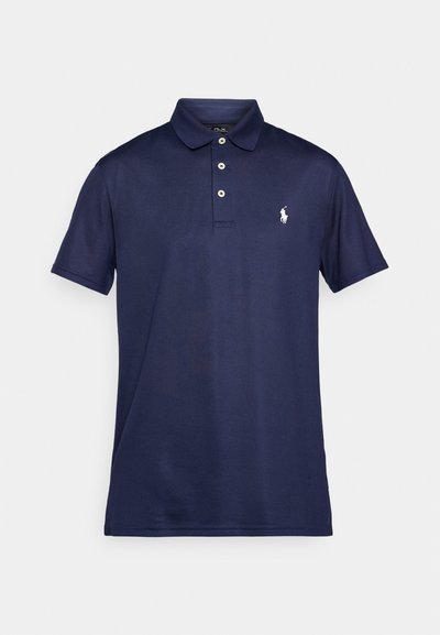 Tumši zilā polo krekls, izgatavots no kokvilnas. Tam ir klasiskā apkakle, trīs pogu atvērums un neliels balts izšūts logo uz krūtīm.