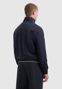 Marineblauwe pullover met een hoge kraag, featuring een losse pasvorm en geribbelde manchetten. Gladde textuur, minimalistisch ontwerp, geen zichtbare patronen of graphics.
