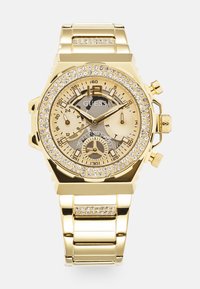 Złoto-tone zegarek chronograf z bezelą zdobioną kryształkami, teksturowaną złotą tarczą, trzema podzegarami i metalową bransoletą.