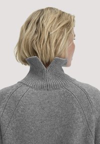 Grauer Strickpullover mit hohem Rippkragen und Raglanärmeln, der eine weiche Textur und ein glattes Finish aufweist.