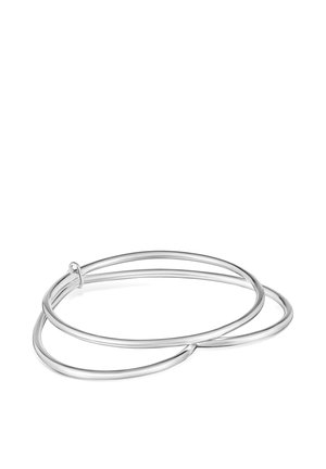 Dwie zazębiające się, gładkie srebrne bransoletki typu bangle bez widocznych zapięć na białym tle.