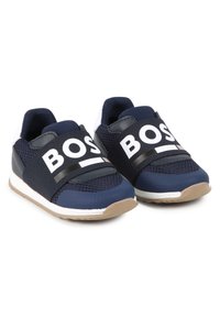Sneakers in rete blu navy con cinturino nero che presenta testo bianco, suola in gomma con accenti beige e collo imbottito per il comfort.