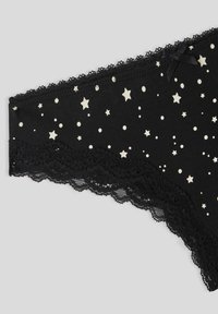 Mutande nere con motivo a stelle e pois bianchi, bordo in pizzo nero lungo i lati e un piccolo fiocco in satin nero vicino all'elastico.