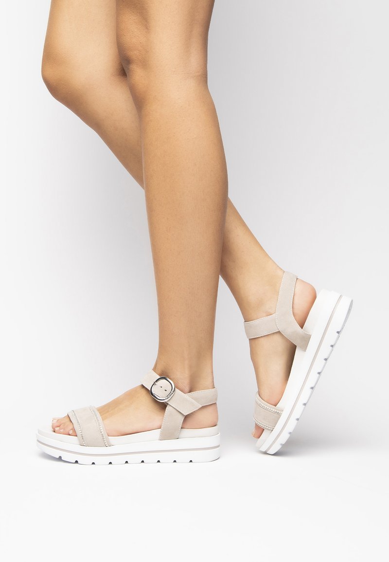 Sandalias de plataforma de ante beige con correa ajustable en el tobillo y hebilla redonda, que cuentan con suela de goma blanca con surcos para mayor agarre.