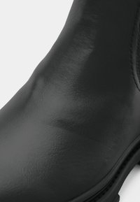 Schwarze Leder-Ankle-Boots mit glatter Textur, runder Zehenpartie und minimalen Nähdetails. Verfügt über eine robuste Gummisohle für guten Halt.