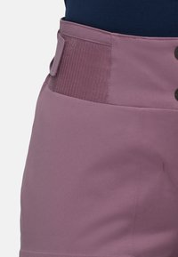Purple sports shorts featuring a textured waistband, button detail, smooth fabric, and a close-fitting design.