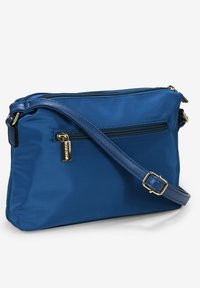 Borsa a tracolla in nylon blu con scomparto principale con zip, una tasca frontale con zip e una tracolla rimovibile. Presenta accenti in metallo color oro.