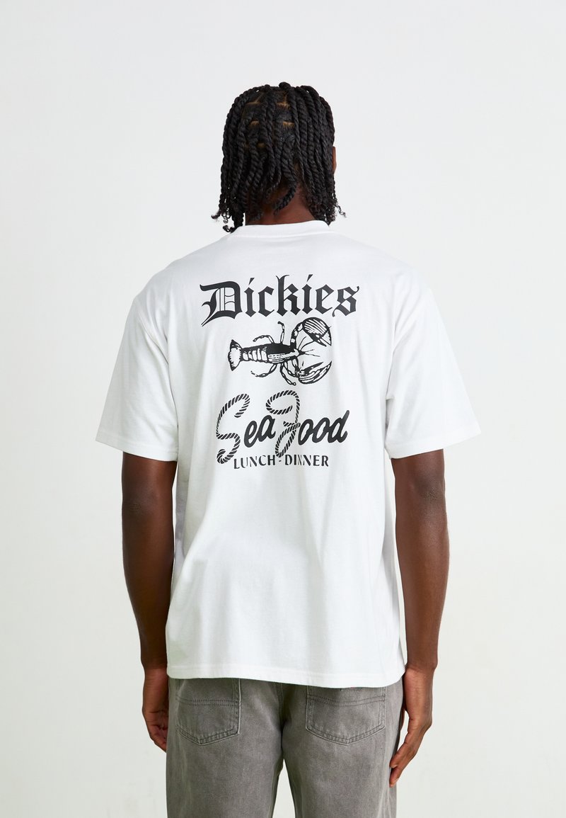 Hvit bomull t-skjorte med et svart grafisk trykk på baksiden, med teksten "Dickies" og "Sea Food Lunch/Dinner," samt en illustrasjon av en hummer.