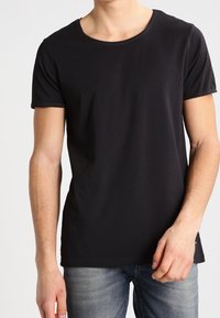 Svart t-shirt med kort ärm och rund halsringning, gjord av mjukt tyg. Kombineras med blå jeans för en avslappnad look.