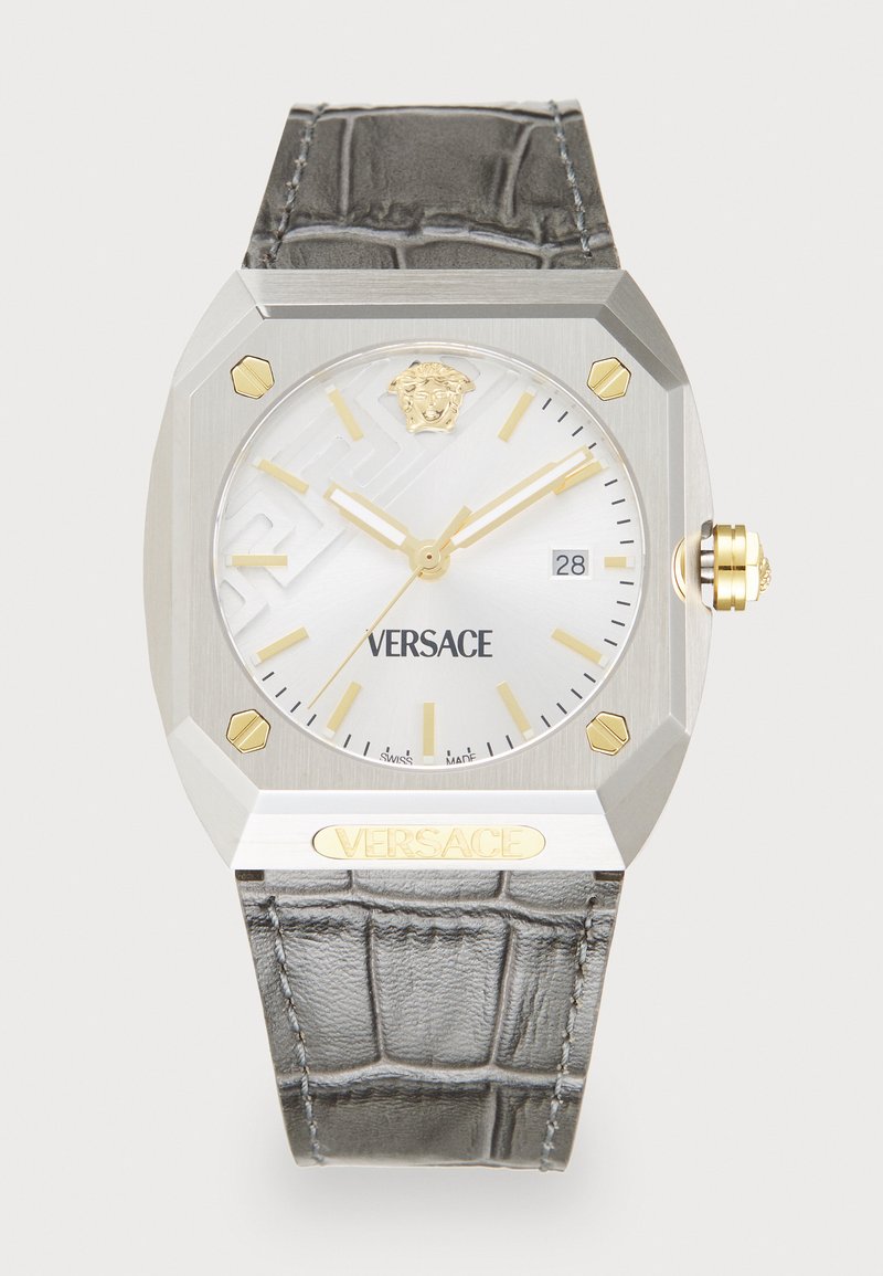 Silver octagonal watch with a mother-of-pearl dial, gold accents, and a textured grey leather strap. Features a date window at 3 o'clock.