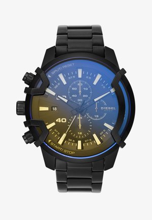 Reloj cronógrafo Diesel de metal negro con tres subesferas, marcadores de hora luminosos, ventana de fecha y botones en el lado izquierdo.