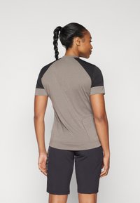 Korte ermer sports topp i grå med svarte ermer og teksturerte detaljer. Kombiner med svarte shorts med subtil merkevare. Glatt stoff.