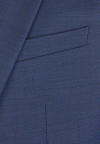 Zbliżenie tkaniny granatowego, teksturowanego marynarki, ukazujące kieszeń pasmanteryjną oraz część szwu klapy.