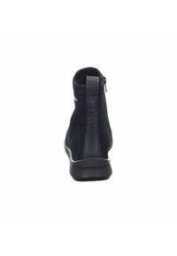 Botín negro de tobillo fabricado en material sintético suave, con cremallera lateral, puntera redonda y suela acolchada. Diseño minimalista.