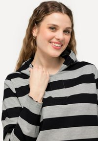 Sudadera con capucha a rayas en gris y negro. Presenta mangas largas, un bolsillo frontal y un corte relajado. La tela parece suave y cómoda.