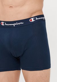 Sötétkék pamut boxer alsó, logós derékpánttal. Szoros illeszkedés, sima textúra és megerősített varrás jellemzi, amely tartósságot biztosít.