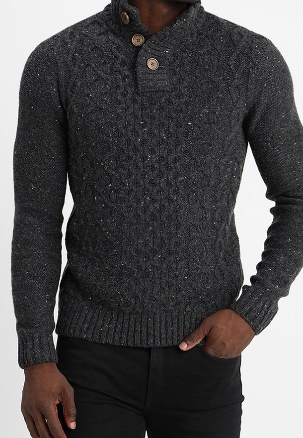 Pull en tricot gris foncé avec un motif texturé, un col haut avec deux boutons ronds en bois, et des poignets et un ourlet côtelés.