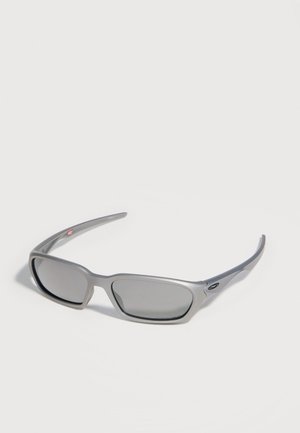 Lunettes de sport rectangulaires grises avec verres teintés foncés et branches fines courbées sur fond blanc.