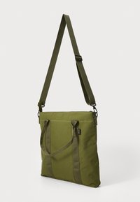 Olijfgroene tote bag met twee handvatten en een verstelbare schouderband, gemaakt van duurzaam materiaal, met een rits aan de bovenkant en voorzakken.