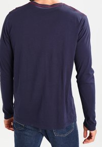 Laivastonsininen pitkähihainen paita pyöreällä kauluksella, jossa on punaista tikkausta kauluksessa, valmistettu pehmeästä puuvillasekoitetekstuuriasta, slim fit -malli.