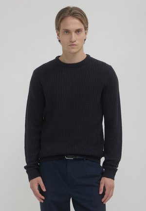Pull en maille texturée bleu marine avec un col ras du cou et des manches longues. Présente un motif en nid d'abeille et des bords côtelés aux poignets et à l'ourlet. Idéal pour un look décontracté.