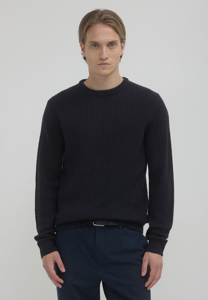 Marineblau gestrickter Pullover mit Rundhalsausschnitt und langen Ärmeln. Mit einem Waffelmuster sowie gerippten Bündchen und Saum. Geeignet für Freizeitkleidung.