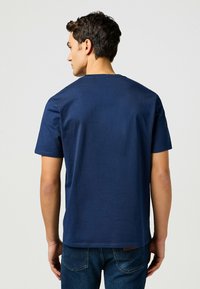 Marinblå bomulls t-shirt med korta ärmar, rund hals och jämn yta. Har en rak nederkant och inga synliga mönster eller accenter.