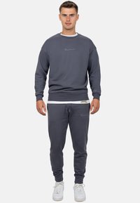 Grijze sweatshirt en jogger set, katoenmix, ribgebreide manchetten, geborduurd logo, casual pasvorm, gelaagd met een wit T-shirt eronder.