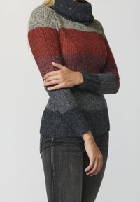 Pull en tricot avec un col haut, dessin rayé rouge, gris et noir, finition texturée et manches ajustées.