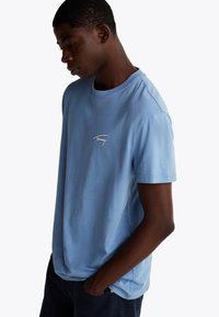 T-shirt di cotone azzurro chiaro con colletto rotondo e maniche corte, con un piccolo logo ricamato bianco sul petto.