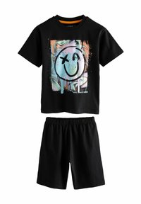 Schwarzes Baumwoll-T-Shirt mit einem bunten Smile-Gesicht-Graphic und dem Text "NYC Skate Vibes", kombiniert mit schwarzen Shorts mit elastischem Bund.
