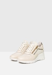 Sneakers sportivi beige con mesh testurizzato e pelle sintetica. Presentano una cerniera decorativa dorata e il logo, suola bianca imbottita.