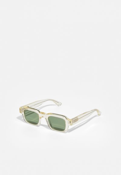 Lunettes de soleil rectangulaires avec des montures jaune clair et des verres vert foncé. Présentent des branches fines et transparentes avec des accents de design subtils.