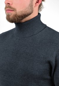 Dunkelgrauer Rollkragenpullover aus feinem Strickstoff. Verfügt über einen hohen gerippten Kragen und eine glatte Textur, die eng am Hals anliegt.