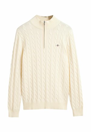Cream-colored cable-knit sweater with a high collar and half-zip closure; features ribbed cuffs and hem, soft texture, and logo accent.