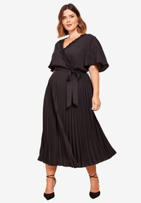 Schwarzes Wickelkleid mit kurzen Ärmeln, plissiertem Rock, Bindegürtel und gewelltem Ausschnitt. Glattes Gewebe ohne sichtbare Muster oder Akzente.