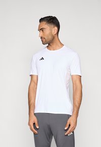 Hvid atletisk T-shirt med korte ærmer og sort trestribet logo, glat tekstur, rund halsudskæring og åndbar paneldetalje på siden.