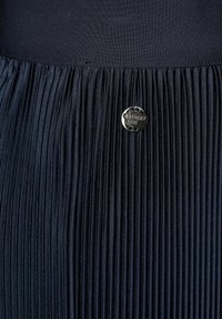 Navy pleated skirt with textured fabric, featuring a round silver tag embossed with the brand name "Street One."