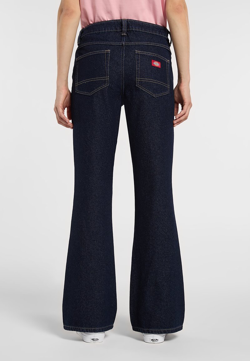 Dark blue flared jeans with a high waist, featuring two back pockets and contrasting stitching. Soft denim texture with a slight sheen.